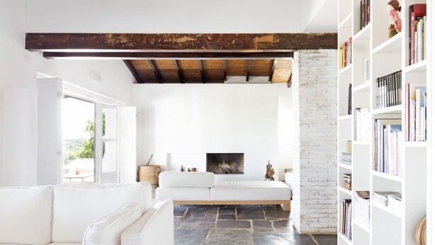 A modern living room with a white sofa, a fireplace, a stone floor, and a bookshelf. - Monte Falperras (Mourão)