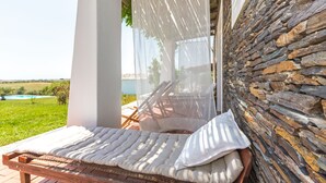 A wooden bench with white cushions and a sheer canopy, positioned against a stone wall. - Monte Falperras (Mourão)