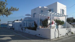 Un edificio moderno blanco con techo plano, un área de estar al aire libre cubierta y vista al mar.