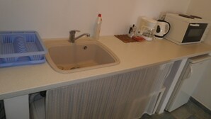 Una cocina con un lavabo, una cafetera y un microondas.