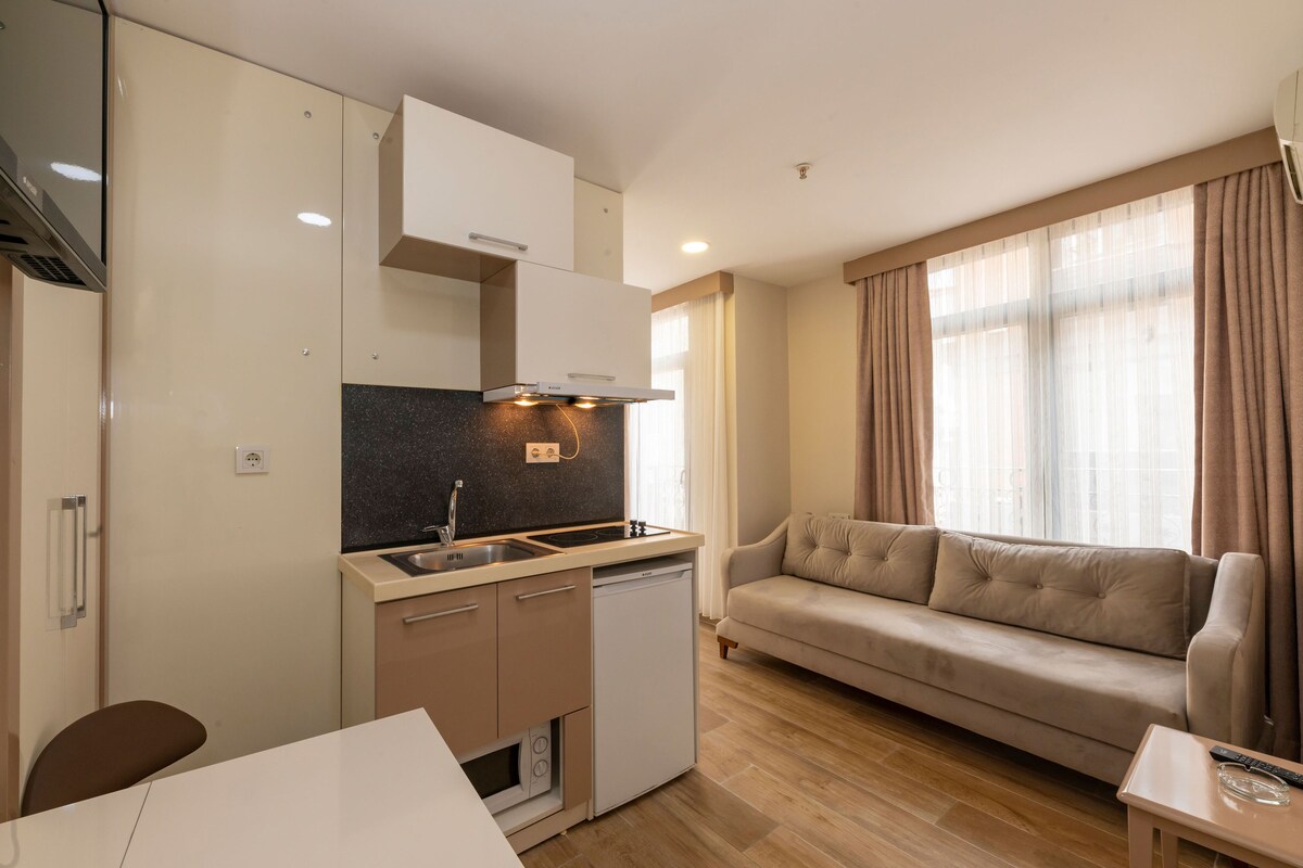 Ett kompakt bostadsutrymme med ett litet kök, en soffa och en matplats.