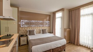 Une chambre d’hôtel comprenant un lit, une table de chevet et un coin cuisine intégré avec un évier et une cuisinière.