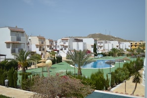 Un resort con varias edificaciones blancas, una piscina y palmeras.