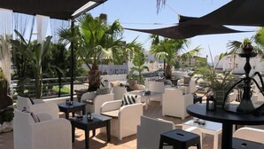 Een terras met rieten meubels, een tafel en een hangplant.