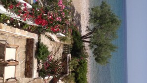 Una proprietà costiera con patio in pietra, recinzione bianca e vista sul mare.