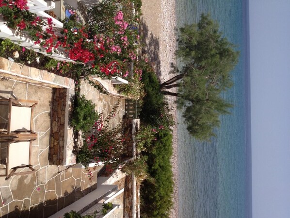 A coastal property with a stone patio, a white fence, and a view of the sea.