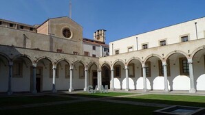 A courtyard with a central open space, surrounded by white buildings with arches and columns. - Aquarooms (Palermo)