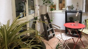 A small patio area with a red table and chairs, surrounded by various potted plants. - Aquarooms (Palermo)