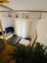 Une pièce comprenant un lit, une petite table, une chaise, une baignoire et une plante.