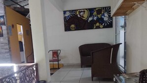 A spacious indoor area with tiled flooring, wicker furniture, and a large abstract painting on the wall. - Suítes São Francisco (Ipojuca)