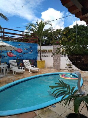 A swimming pool with lounge chairs and a mural of fish. - Suítes São Francisco (Ipojuca)
