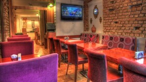 A restaurant with wooden flooring, red cushioned booths, and a brick wall. - Tamara Suite Hotel (Istanbul)
