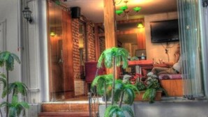 A hotel entrance with a wooden door, a staircase leading inside, and a seating area with chairs and potted plants. - Tamara Suite Hotel (Istanbul)