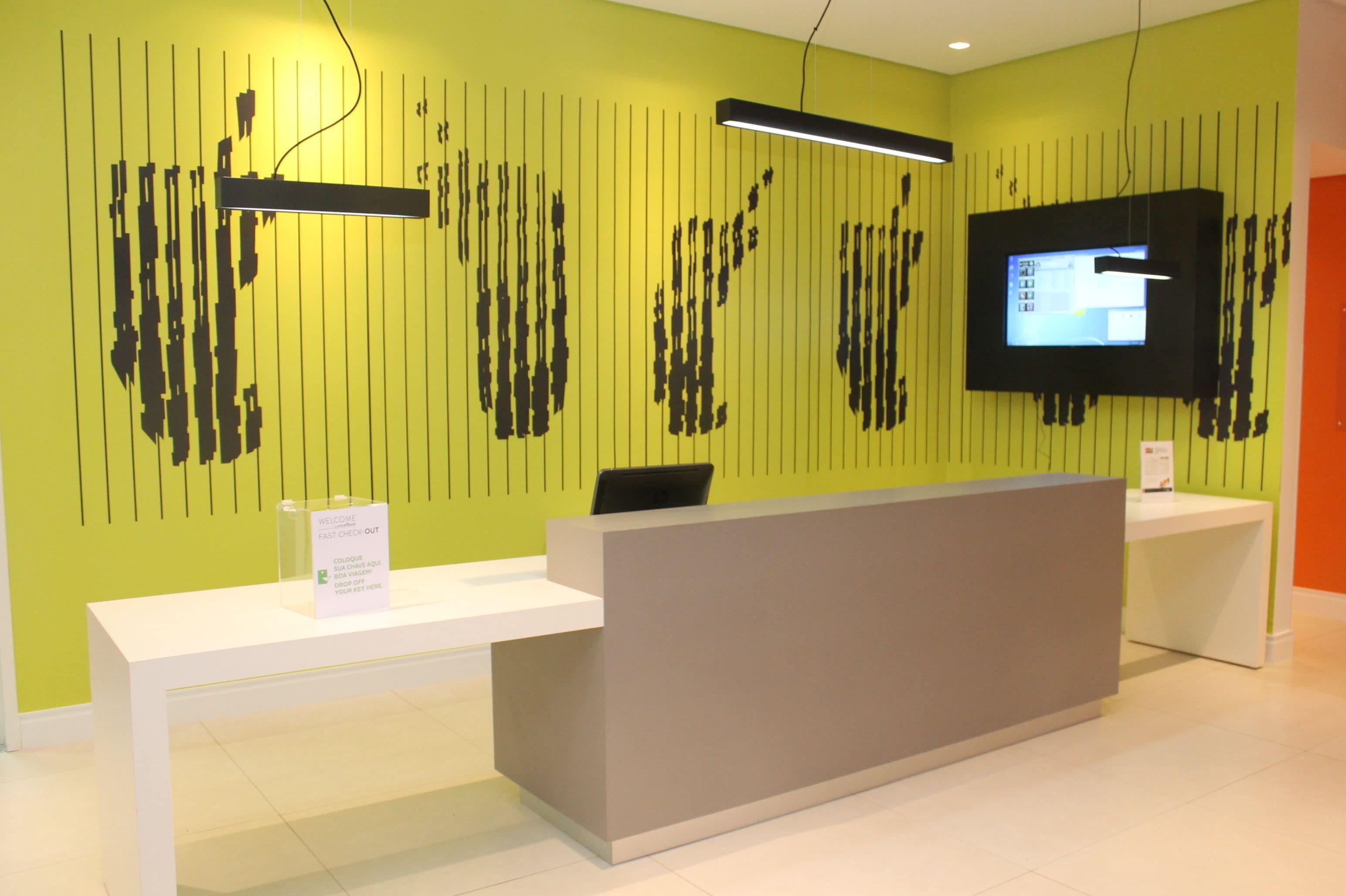 A reception desk with a flat-screen TV, a modern light fixture, and a sign indicating a fast check-out process.