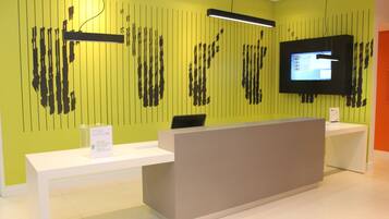 A reception desk with a flat-screen TV, a modern light fixture, and a sign indicating a fast check-out process.