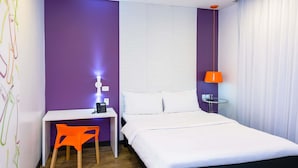 Une chambre d’hôtel comprenant un lit, un bureau, une chaise, une lampe et une table de chevet.