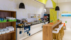 Un café moderne avec un comptoir, des places assises et un mur décoré de motifs de feuilles.