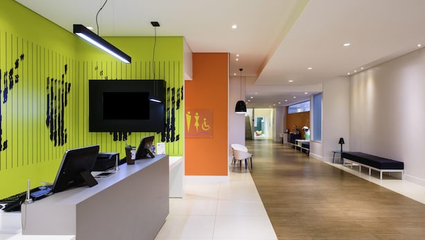 Un espace d’accueil moderne doté d’un mur végétal, d’un téléviseur à écran plat et d’un bureau équipé d’ordinateurs.