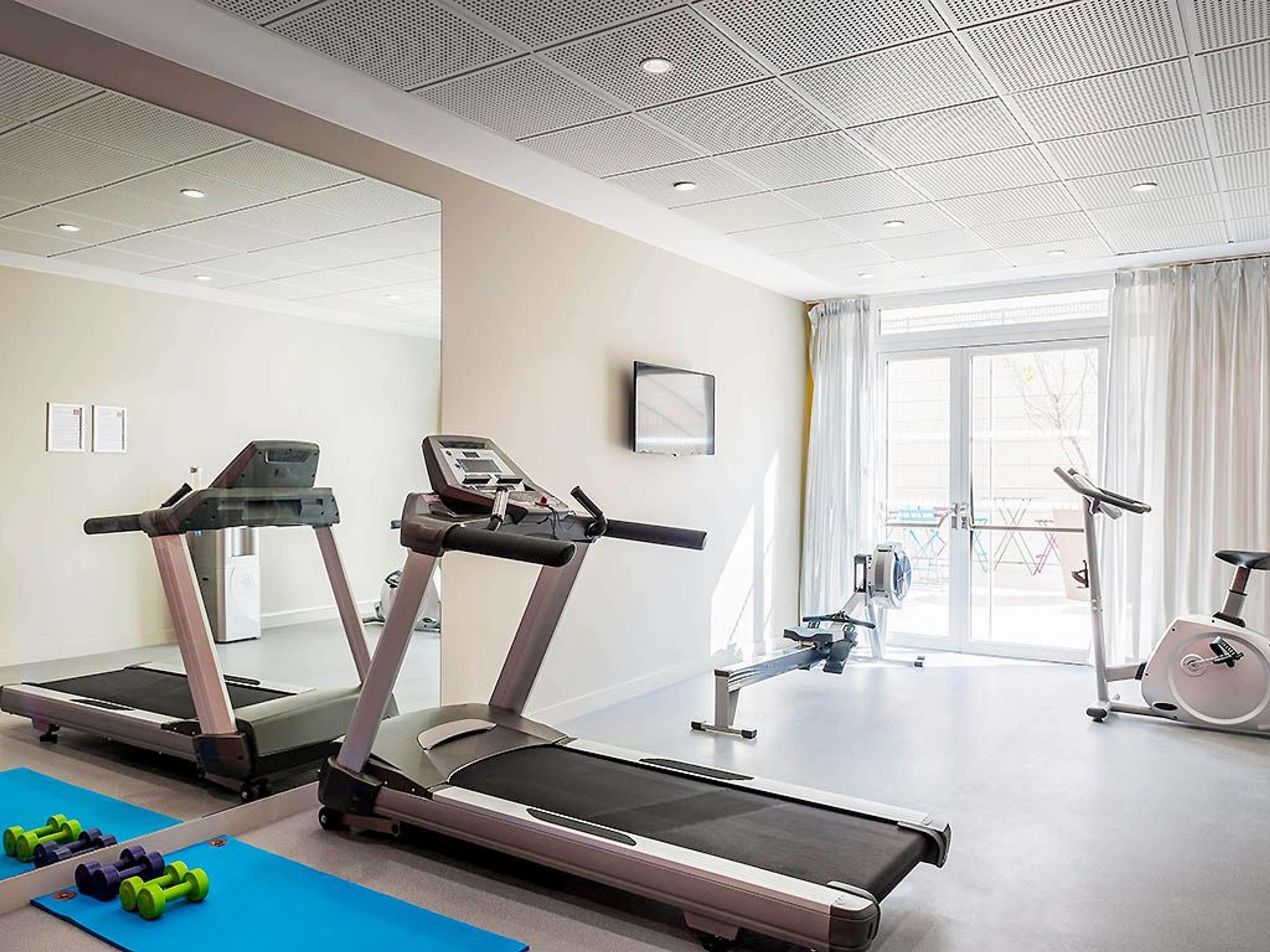 A gym with treadmills, dumbbells, and exercise bikes.