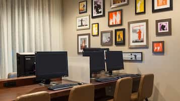 Un salón de conferencias con varias estaciones de trabajo, cada una equipada con monitor, teclado y ratón.