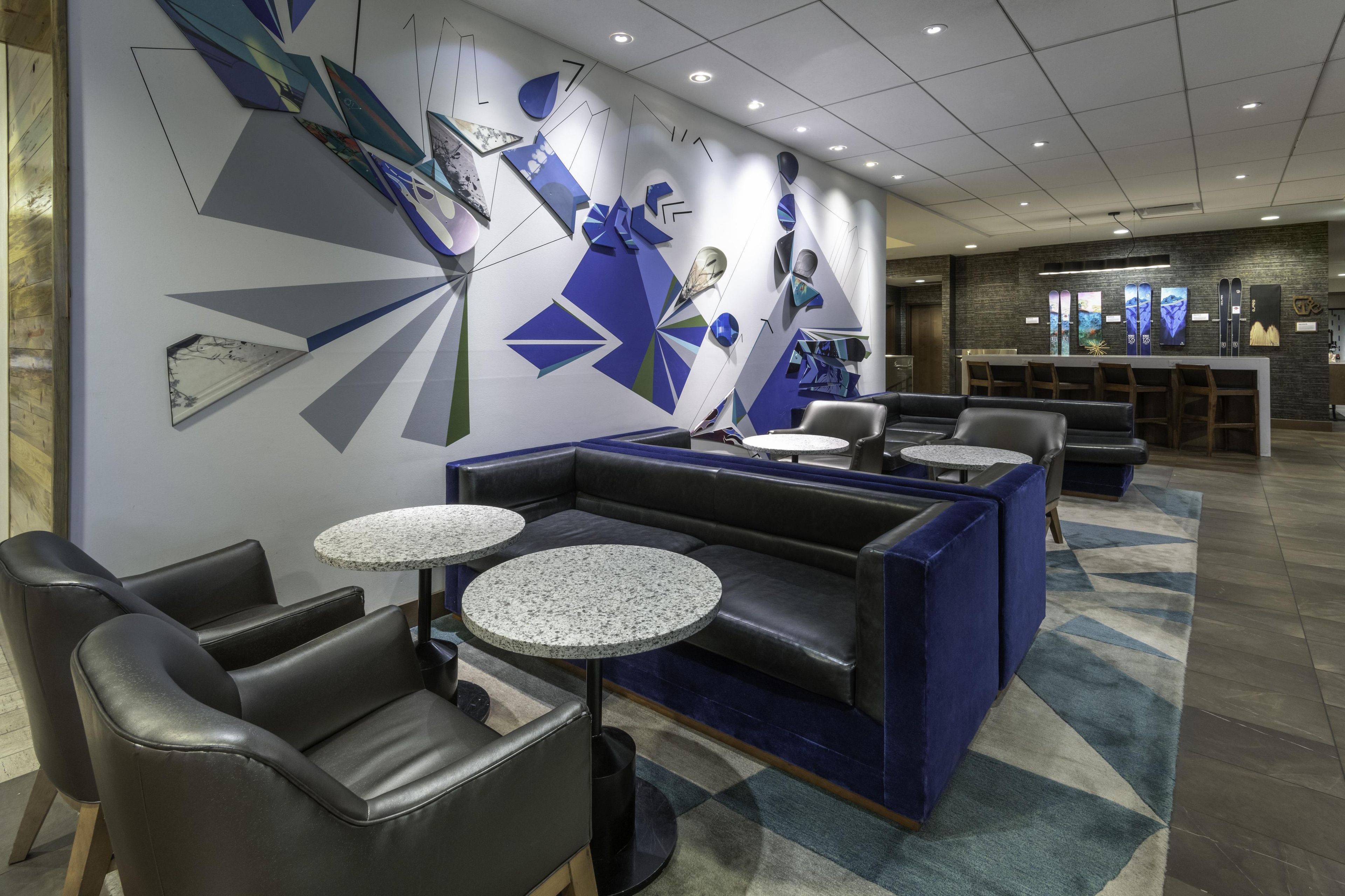 A modern lounge area with seating, tables, and a decorative wall.