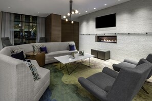 A modern living room with a sectional sofa, armchairs, a coffee table, a fireplace, and a TV mounted on the wall. - Hyatt Place Denver Downtown (Denver)