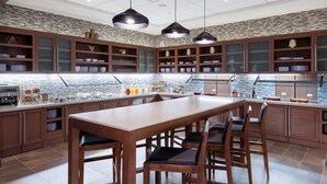 A modern kitchen with a central island, wooden cabinets, and pendant lighting. - Hyatt Place Denver Downtown (Denver)