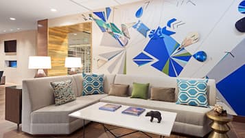 A modern living room with a sectional sofa, a coffee table, and a decorative wall with geometric patterns.