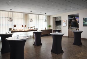 A modern lounge area with round tables, a bar, and large windows. - Hyatt Place Denver Downtown (Denver)