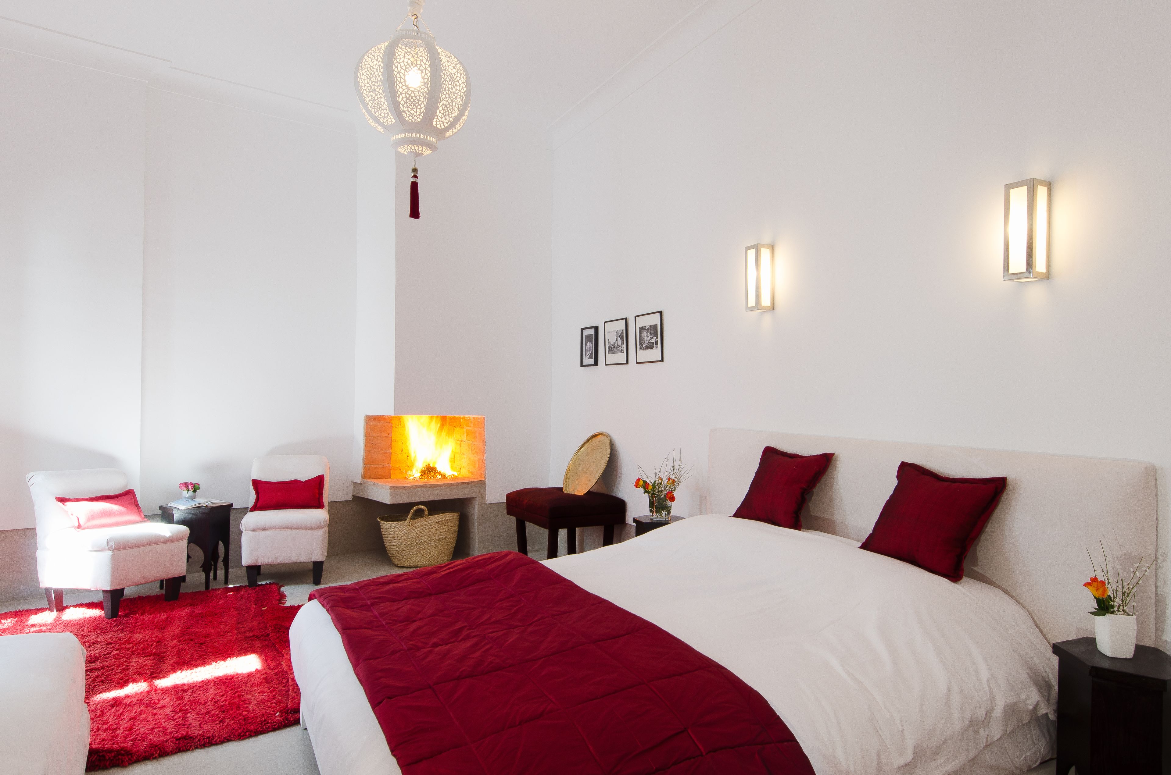 Ein modernes Hotelzimmer mit einem großen Bett, zwei weißen Sesseln, einem kleinen Tisch mit einer Lampe und einem Kamin.