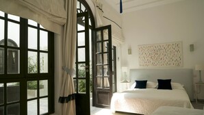 Une chambre d’hôtel avec deux lits, de grandes fenêtres et une vue sur la verdure environnante.
