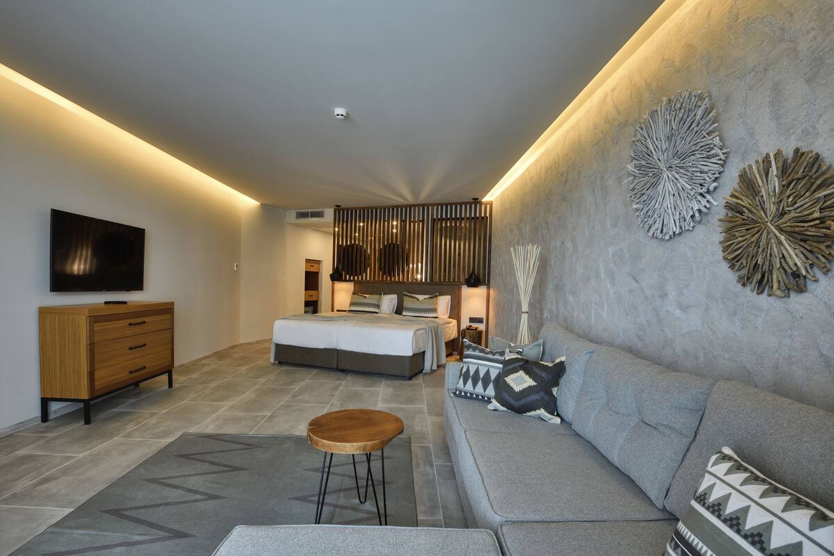 A modern bedroom with a bed, bedside tables, a TV, and a sofa.