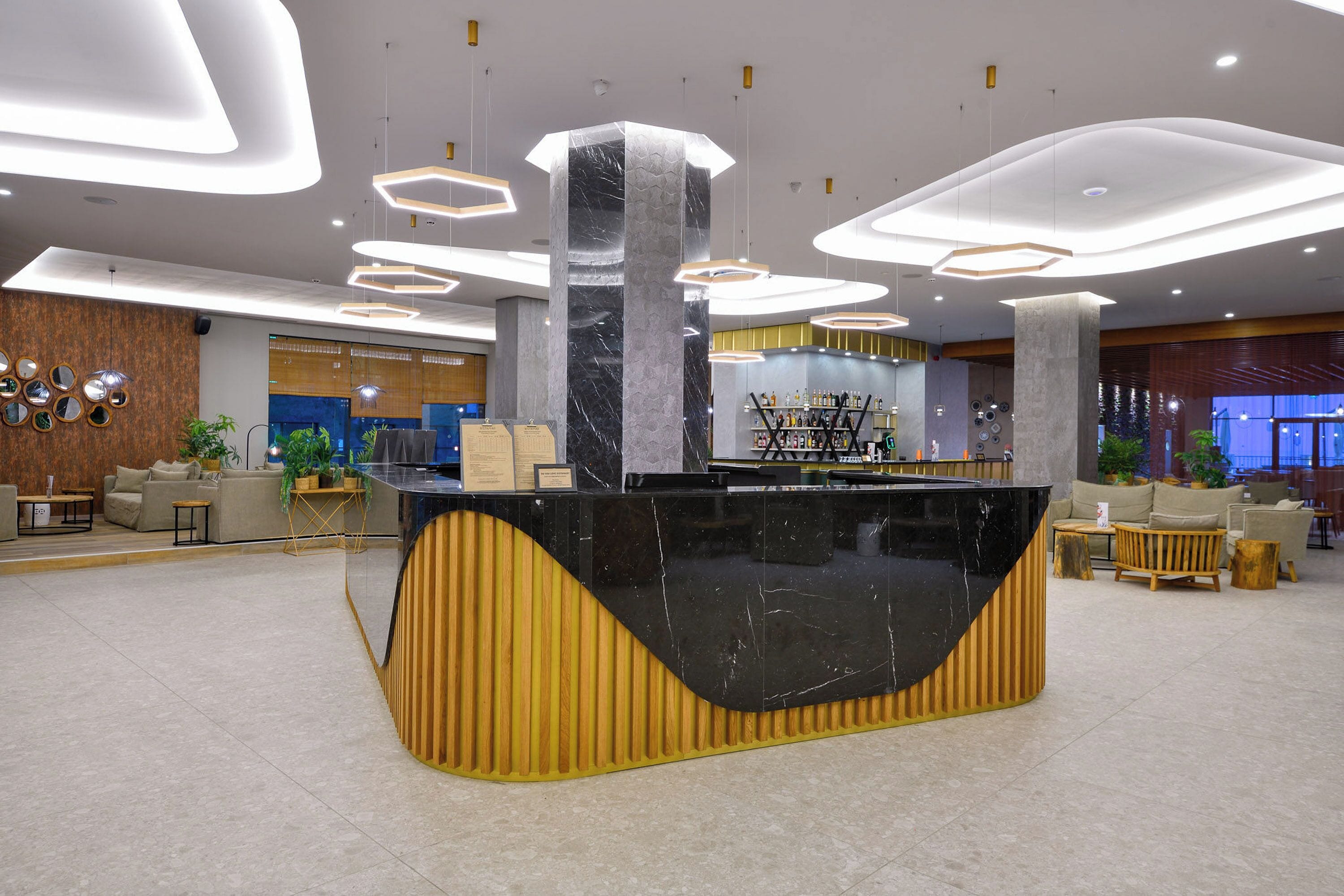 A modern reception area with a curved black reception desk, wooden accents, and contemporary lighting fixtures.
