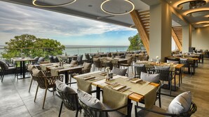 An outdoor dining area with tables and chairs, a view of the sea, and a wooden staircase. - Grifid Hotel Vistamar - Ultra All Inclusive (Golden Sands)