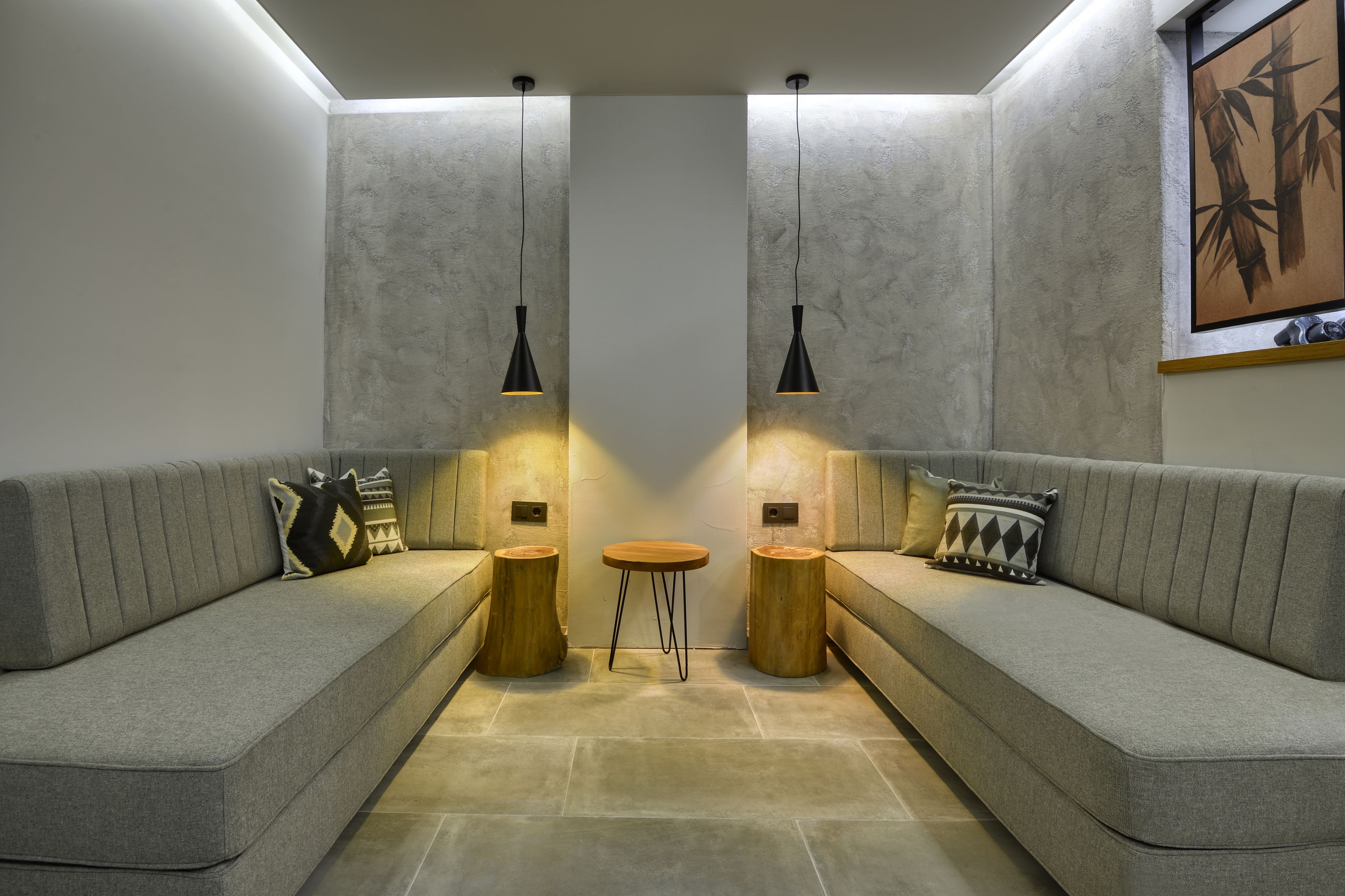 A modern living room with a grey sofa, two wooden side tables, and pendant lights.