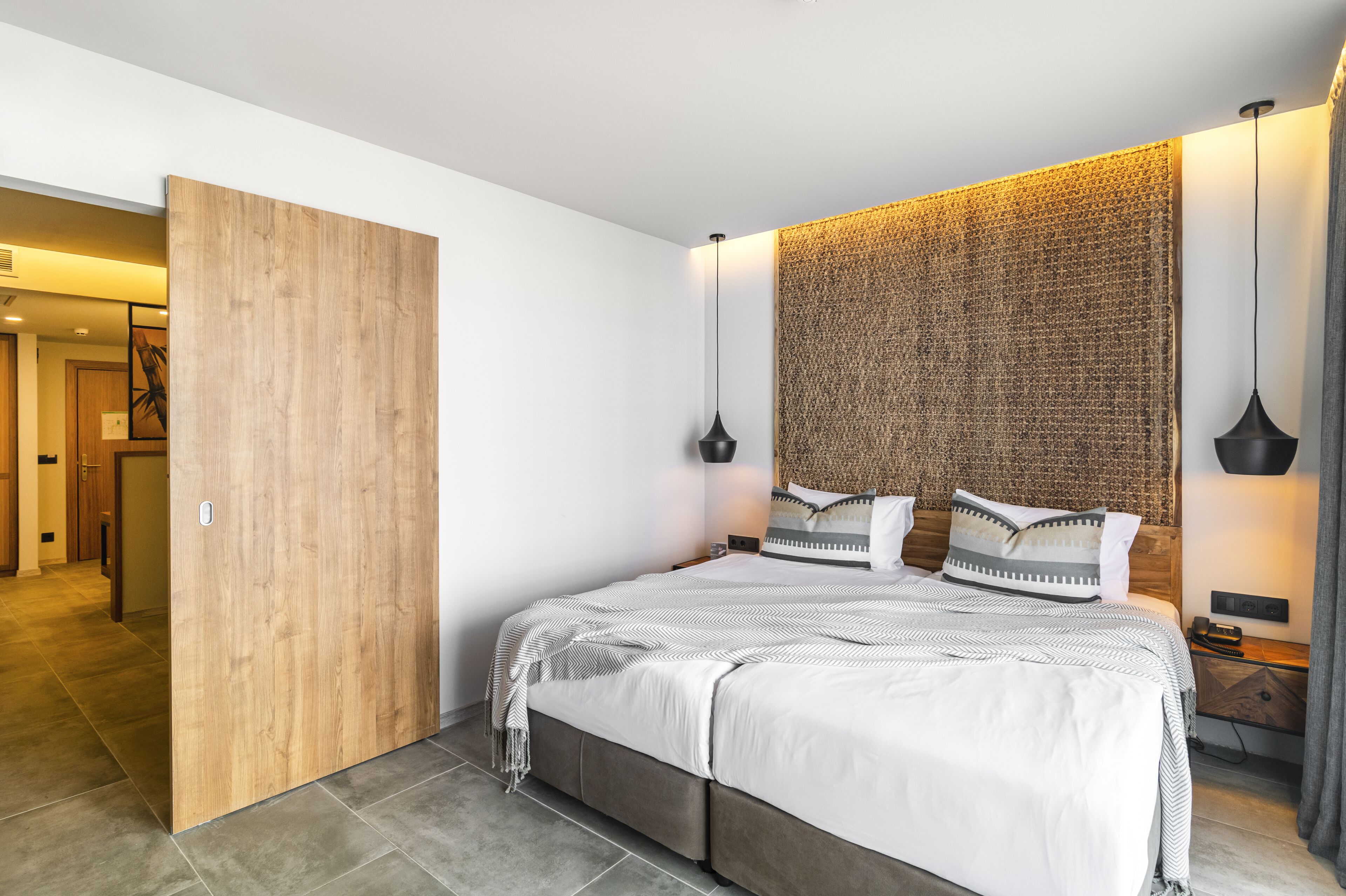 Een moderne slaapkamer met een groot bed, een houten schuifdeur en een structuurmuur.