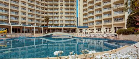 Un hotel con piscina, varios balcones y cielo despejado.