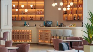 Eine Bar mit Regalen voller Flaschen und Gläsern, einer Theke und Sitzgelegenheiten mit runden Tischen und Stühlen.