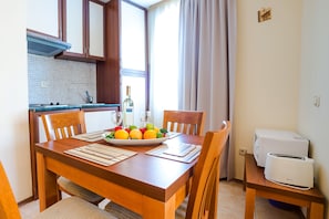 A dining table with chairs, a plate of fruit, a bottle, and a toaster. - TSB Sunny Victory Apartments (Sunny Beach)