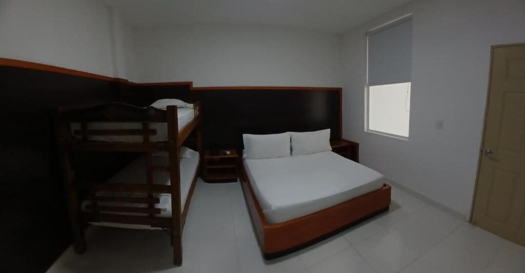 A room with a bunk bed, a single bed, a nightstand, and a window.