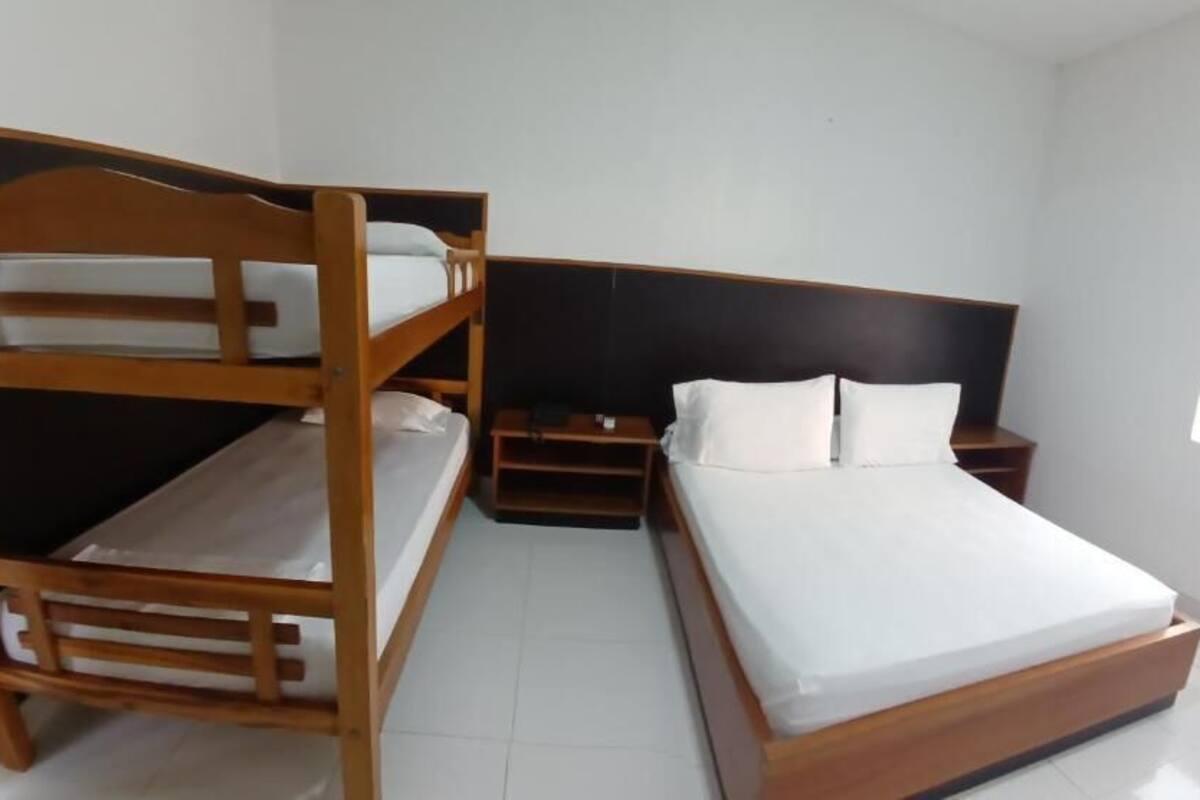 Habitación con literas, una cama individual y una mesita de noche.