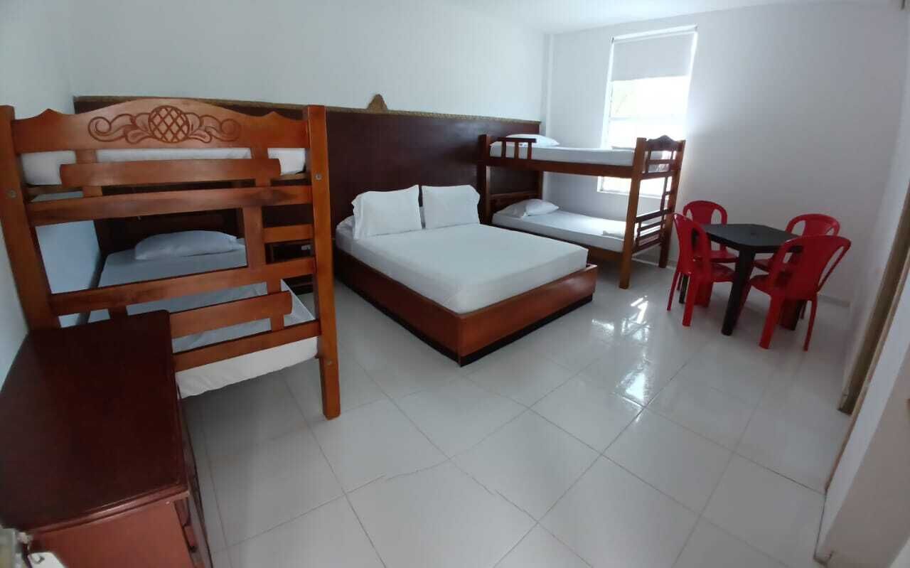 A room with bunk beds, a small table, and red chairs.