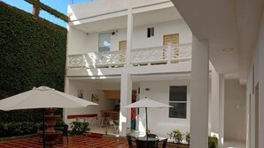 Une cour avec un bâtiment blanc, des sièges en plein air et une fontaine décorative.