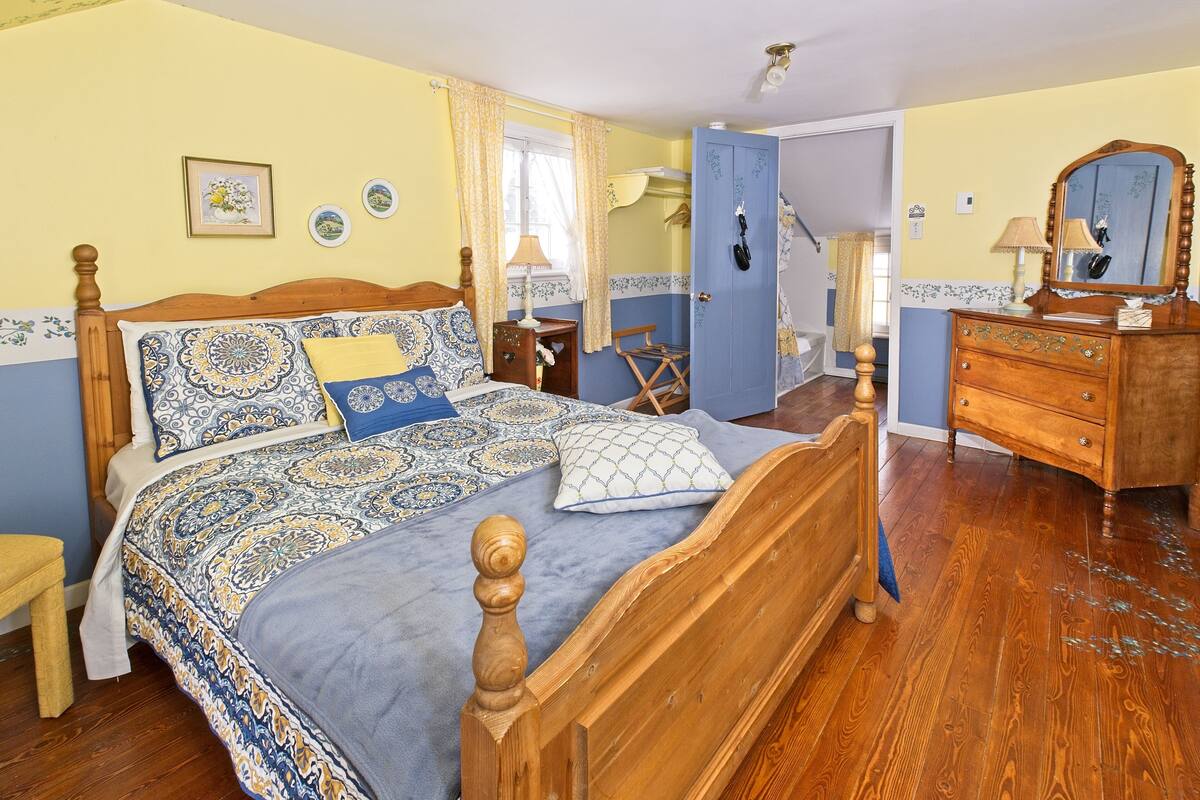 A bedroom with a wooden bed, a dresser, a chair, and a mirror.