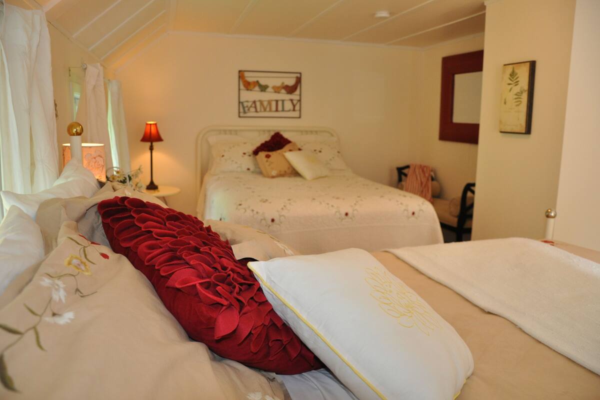 A bedroom with two beds, a bedside table with a lamp, and a wall with a 'FAMILY' sign.