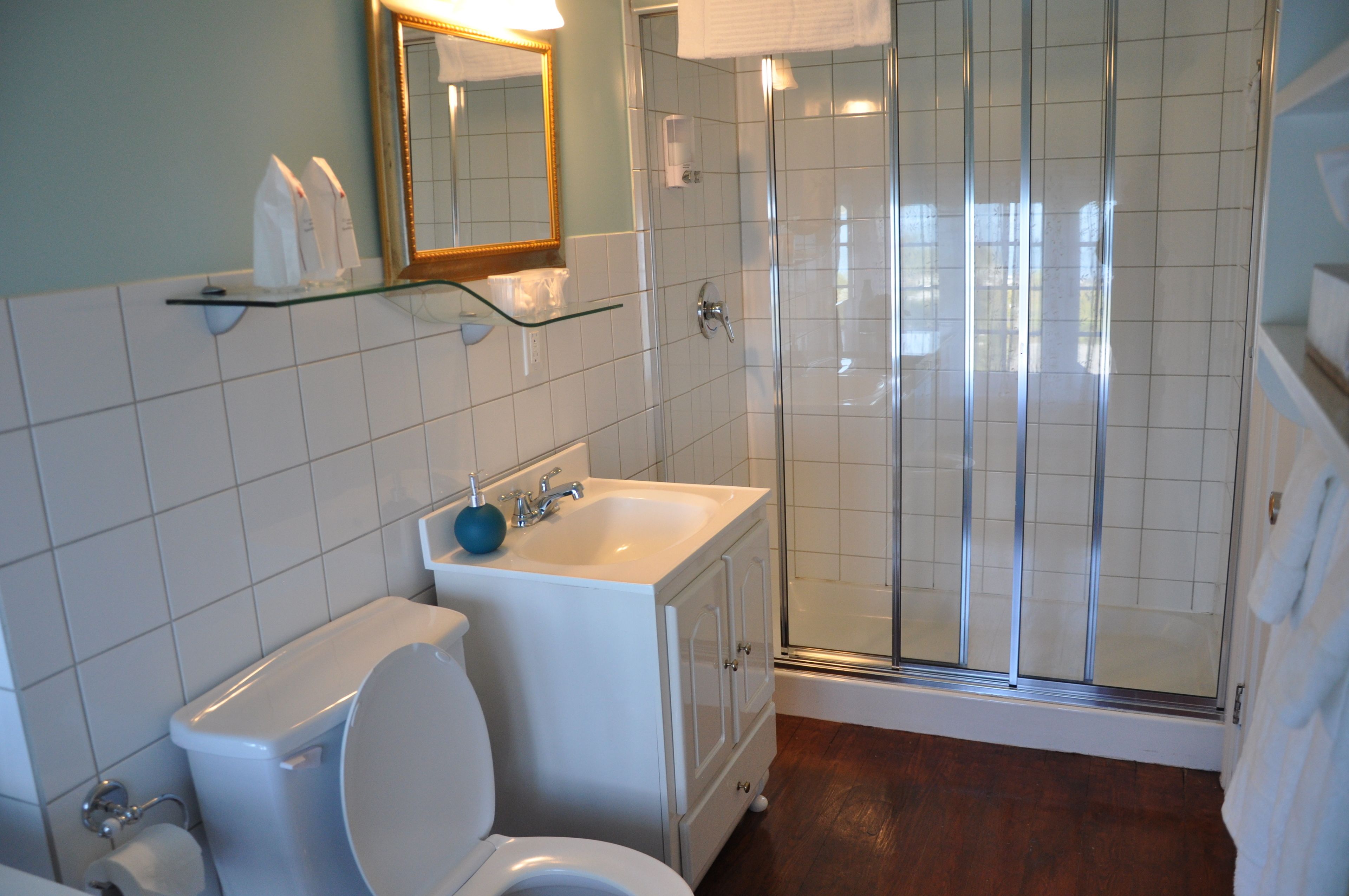 Un baño con inodoro, lavabo y cabina de ducha de vidrio.