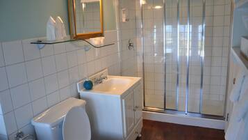 Un baño con inodoro, lavabo y cabina de ducha de vidrio.