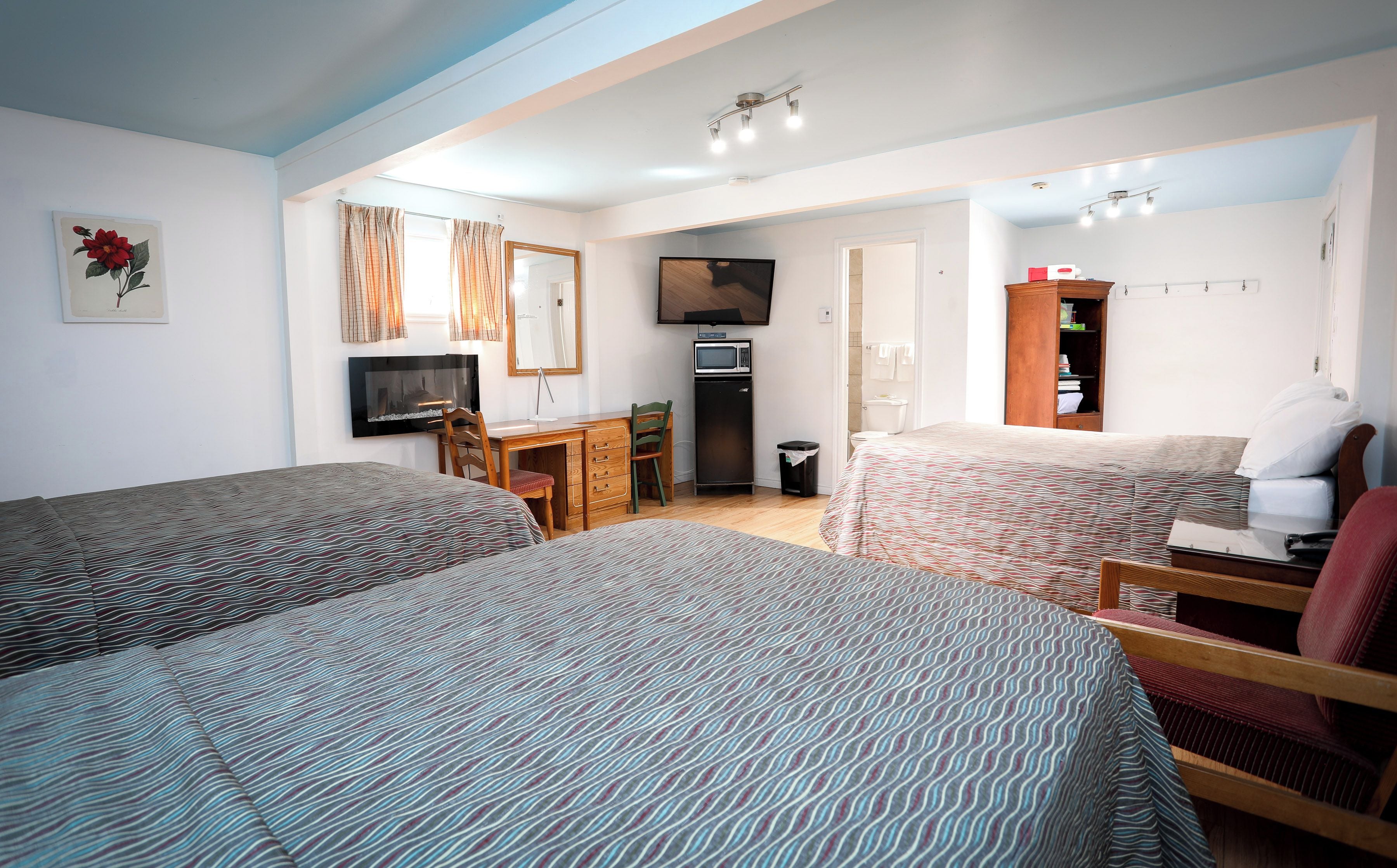 A hotel room with two beds, a desk, a television, a wardrobe, and a bathroom.