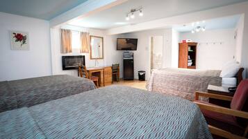 A hotel room with two beds, a desk, a television, a wardrobe, and a bathroom.