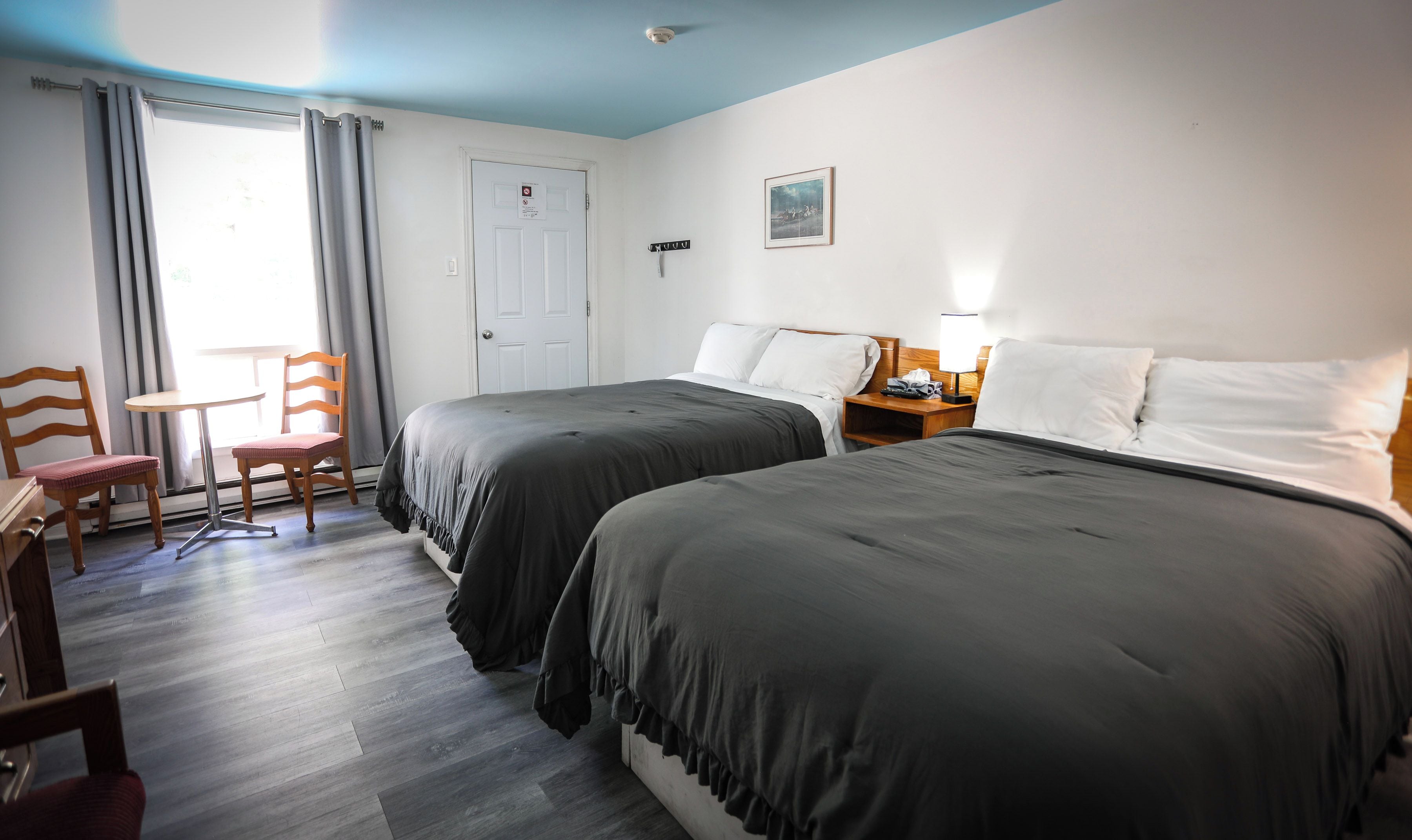 Una habitación de hotel con dos camas, un escritorio, una silla y una puerta.